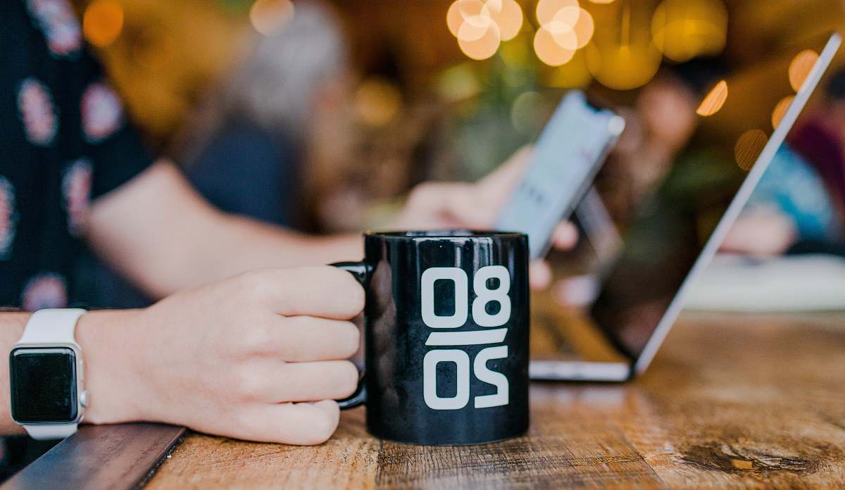 coffee cup person working on laptop phone